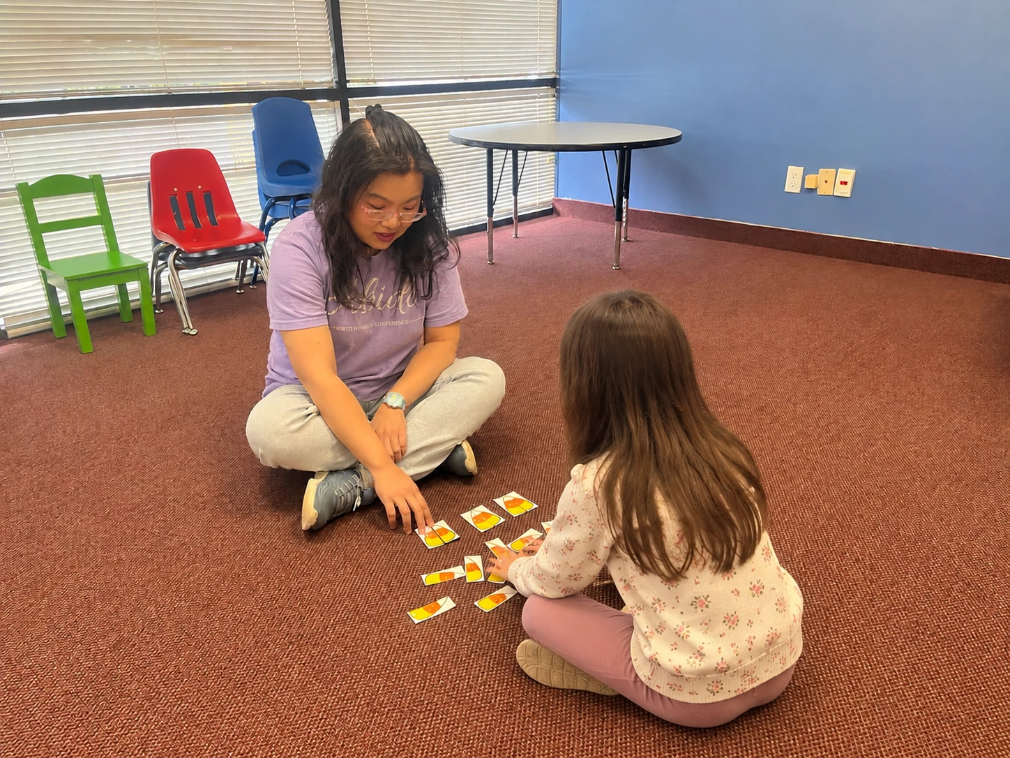 A teacher and child playing a music card game on the classroom floor