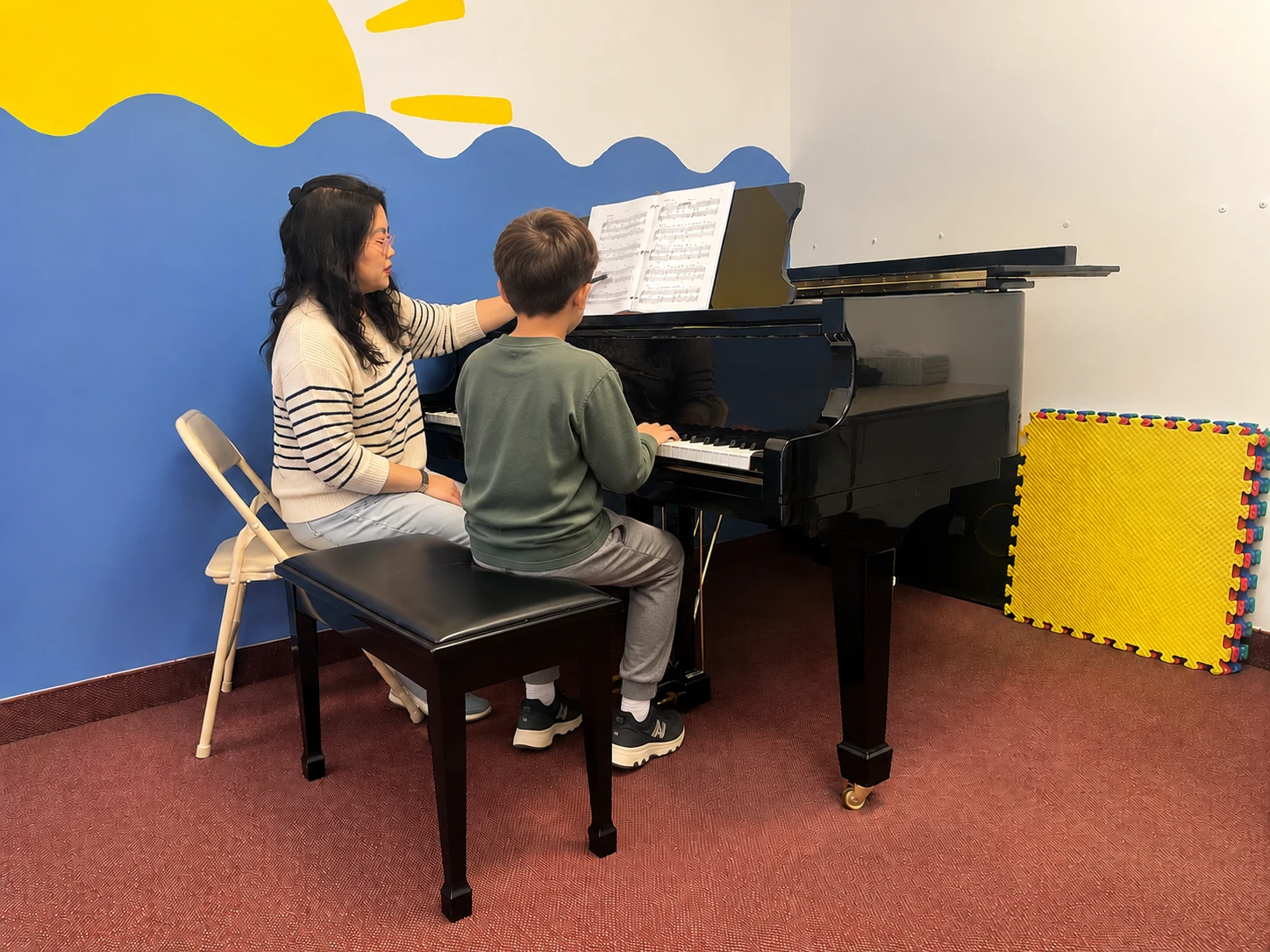 A teacher and young student at the grand piano during a lesson